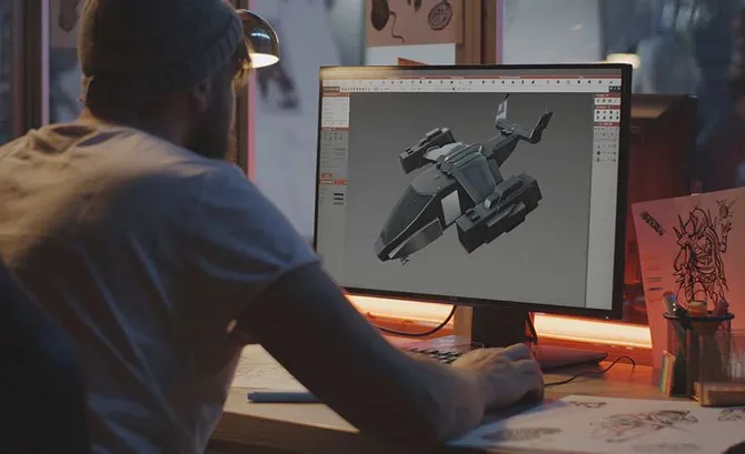 An over the shoulder view of a student working on designing a game on a computer.