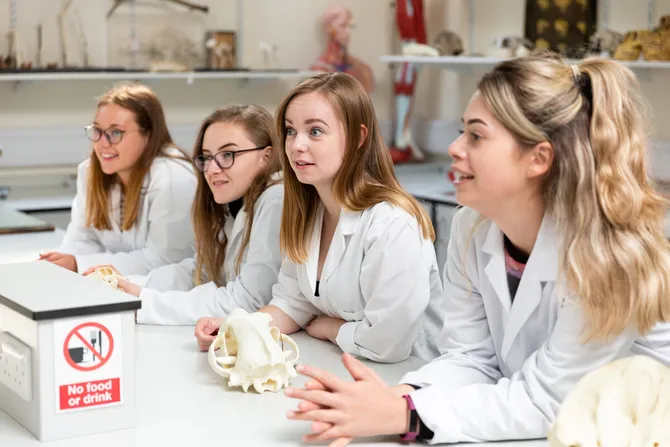 group of international wildlife biology students in lab looking at skulls