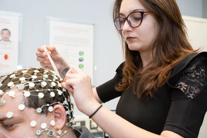 A student is placing a brain cap onto another students head.
