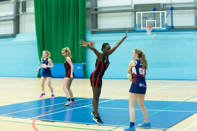 A student is thinking of passing the netball, but is being blocked by another player.