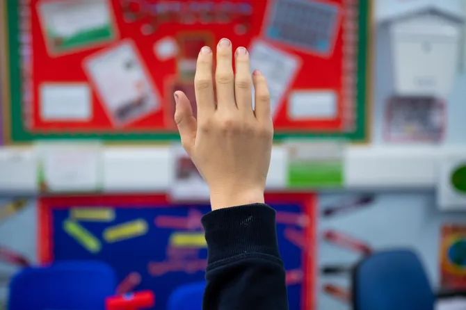 A childs hand raised in a classroom