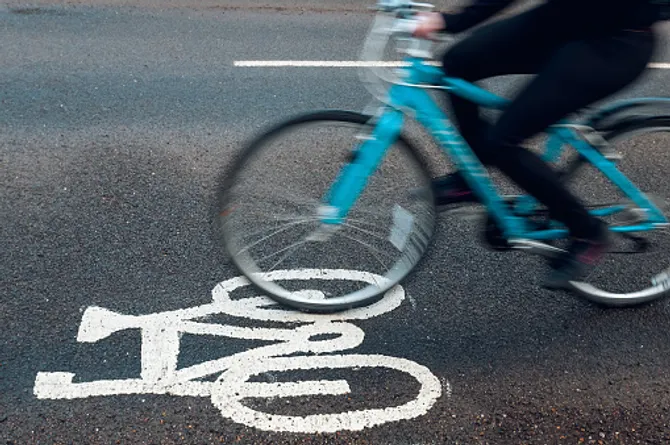 A bike driving along a road with a bike symbol painted on the floor.