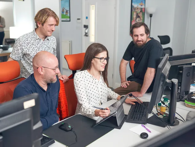 A group of researchers gather around a computer for a group project