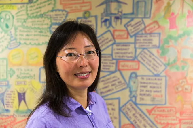 Dr Juping Yu standing in front of wall in Genomics Policy Unit