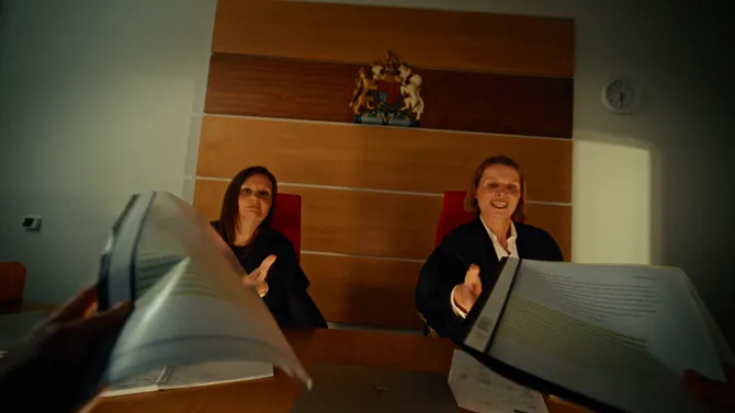 Two hands reaching up to give judges folders of papers during a court session.