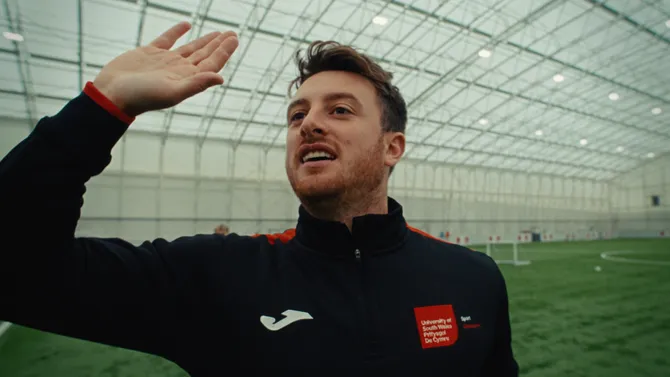 Close up shot of sporting lecturer raising his hand whilst talking to students