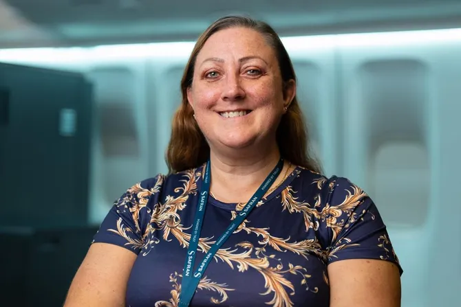 Network75 and Degree Apprenticeship employer Joanna Kerrigan smiles at the camera while wearing a blue lanyard in front of an office space