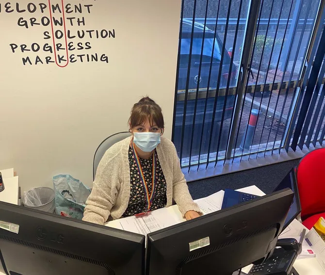 wales contact centre forum worker sitting at a desk wearing a face mask