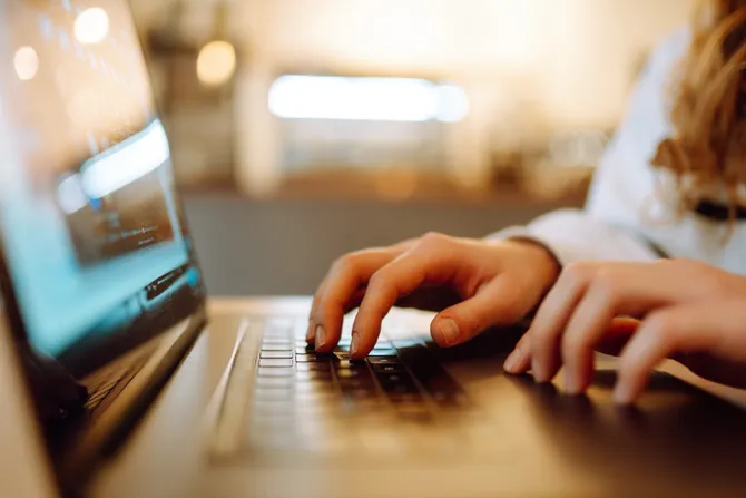 A close up of fingers typing on a laptop keyboard.