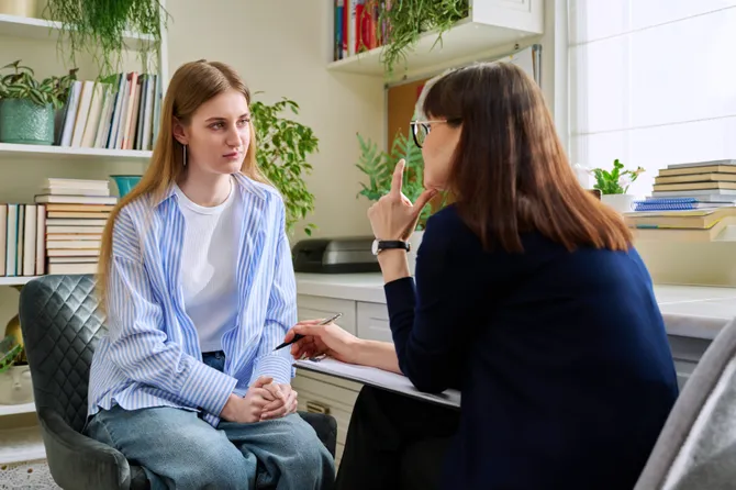 Young teenage female patient talking to professional mental therapist.