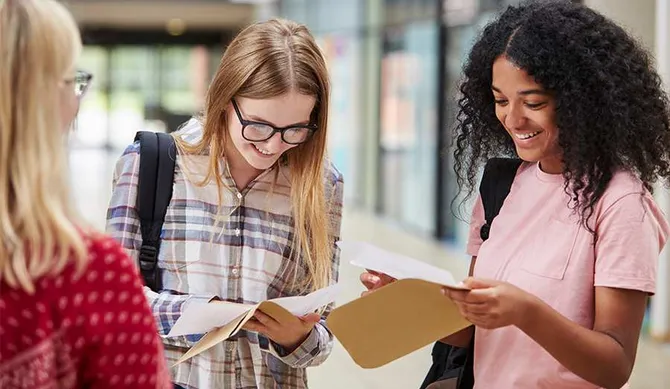 A group of students opening envelopes to discover their exam results.