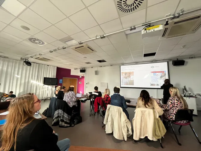 A room of people listening to a seminar being delivered by Paul Campbell.