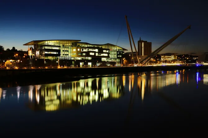 A riverside view of the Newport Campus at night.