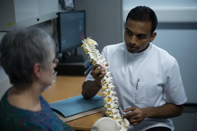Chiropractic student holding a model spine during a consultation at the chiropractic clinic