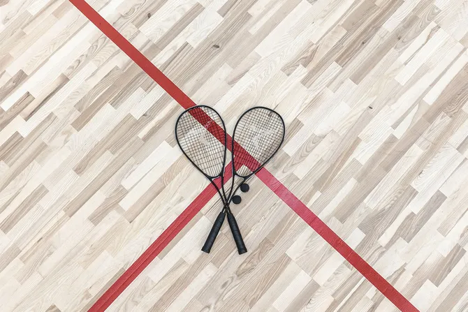 Two squash rackets and a ball placed on the floor of a squash court