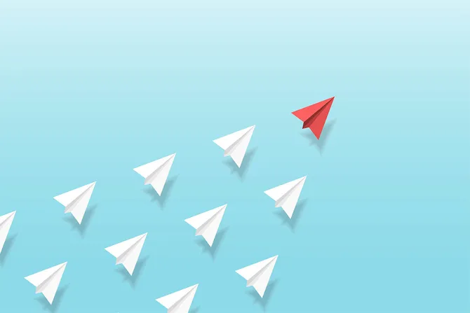 Origami paper planes with one red plane leading the group