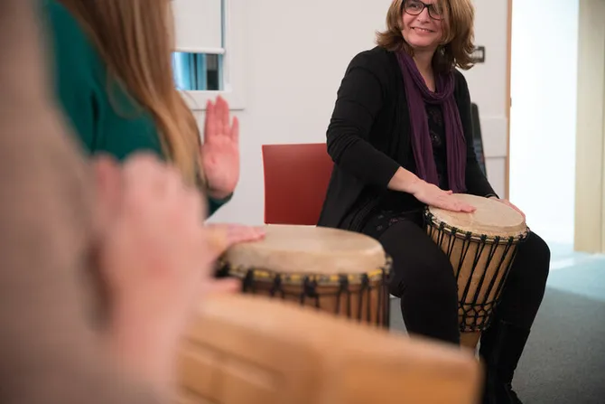 A group of music therapy students sat together playing bongo drums,