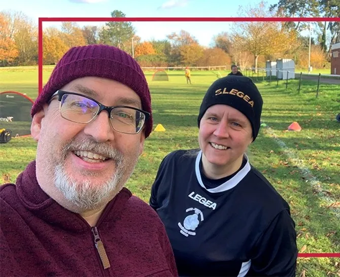 Neil Gibson and Natalie Kendrick-Doyle smiling to camera standing on an outside football picth
