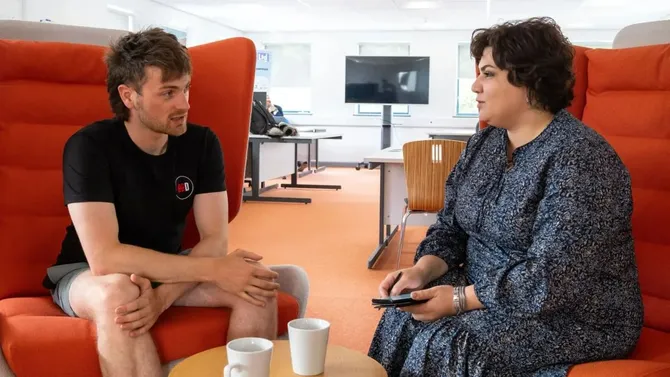 Two members of USW Enterprise staff sat in chairs facing each other talking