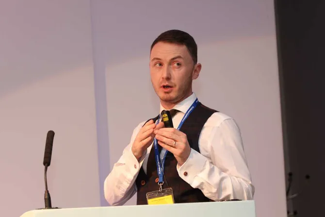 Gareth Davies standing at a podium presenting