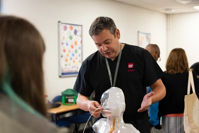 A lecturer is demonstrating nursing equipment at an Open Day.
