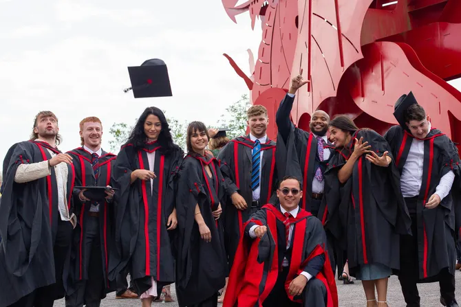 Students wearing graduations gowns and caps celebrating in a group