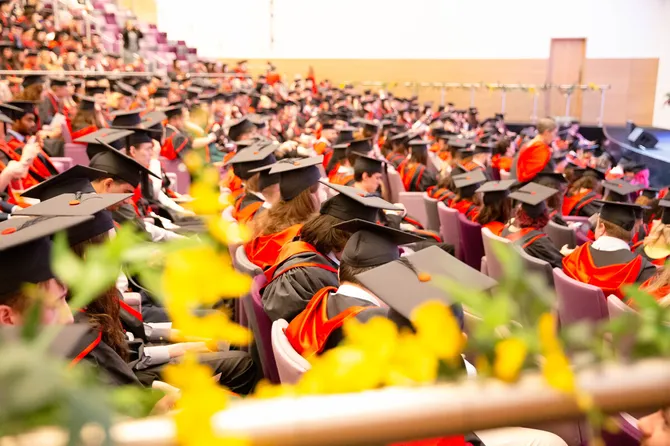 The auditorium of Newport's ICC packed with students dressed in graduation gowns and caps watching their graduation ceremony