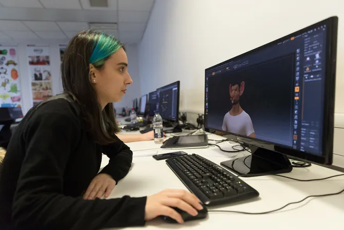 student in classroom using computer and looking at screen with a cgi visual of a man on screen