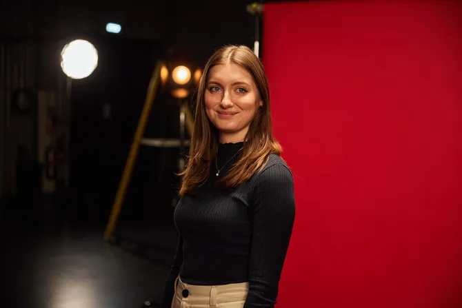 image of business student smiling looking towards the camera with a red backdrop