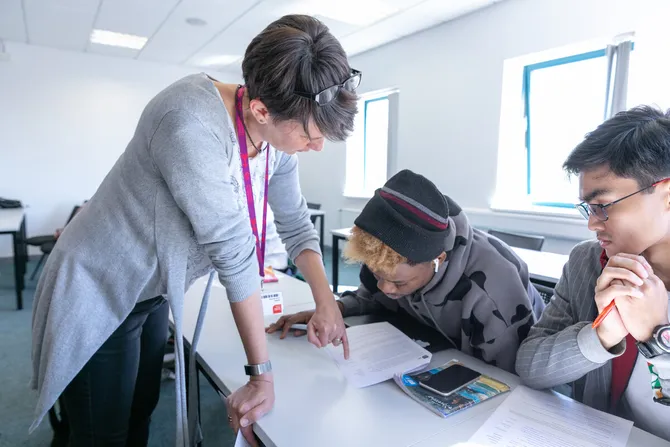 Academic staff talking to students in class