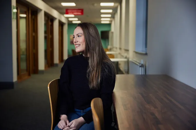 A student sat on a chair in a corridor looking to left of the camera