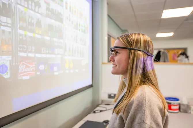 A student is taking part in a class activity. They are wearing a pair of technological glasses which is recognising images on a screen.