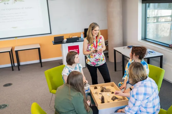 A group of Therapeutic Studies and Counselling students chatting in a classroom with a lecturer