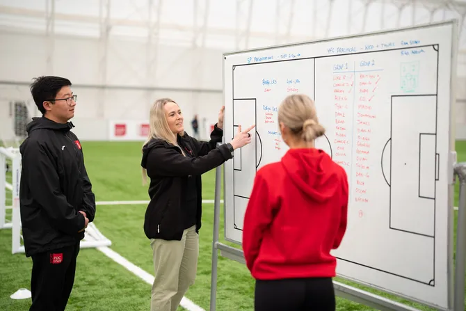 Students are looking at a white board discussing game techniques.