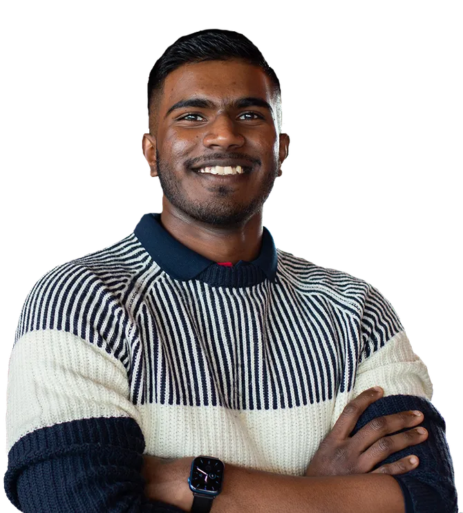 An image of a student smiling at the camera with their arms folded