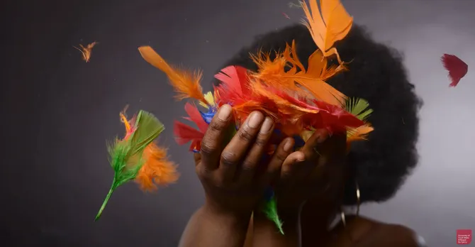 Photograph of student work - student holding colourful feathers