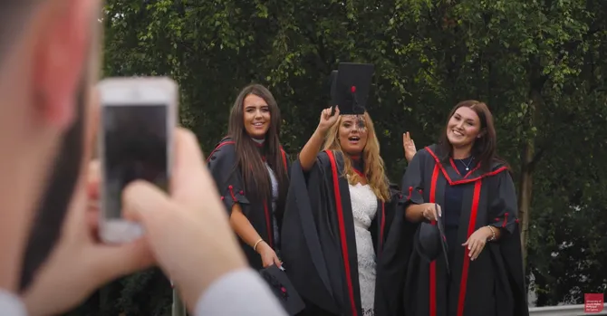 three usw graduates posing for a photograph in graduation robes