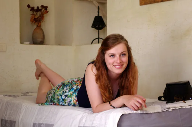 international wildlife student Livvy lay on a bed leaning on elbows with feet in the air behind her