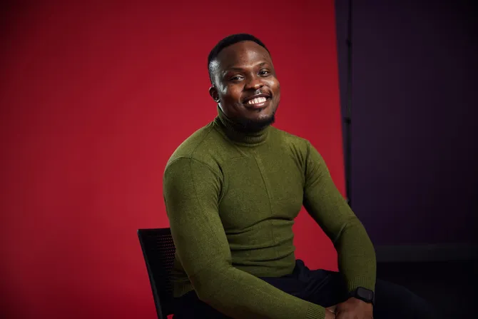 Chidiebere Ejiogu smiling to camera in front of a USW red background