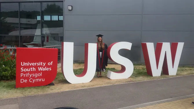 medical sciences graduate francesca saleh posing with USW sign on Pontypridd campus, Treforest at graduation