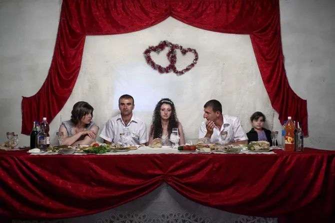 photography by anastasia taylor lind of a wedding dinner table with food and five family members sitting in a line