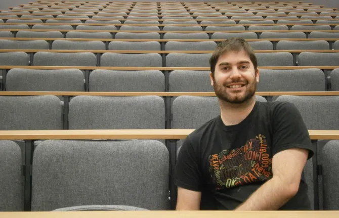 psycholofy with counselling student, Ross, sitting in an empty lecture theatre smiling to camera