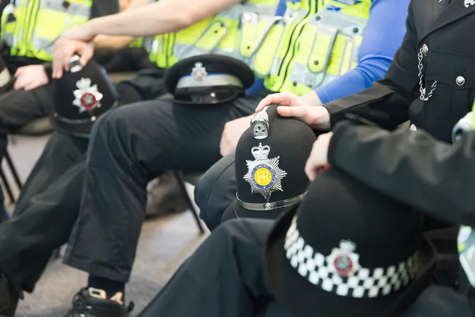 A group of police officers sat with their helmets resting on their knees