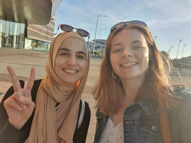 Graduate, Ellie Rose, and a friend are smiling and taking a selfie in Cardiff Bay.