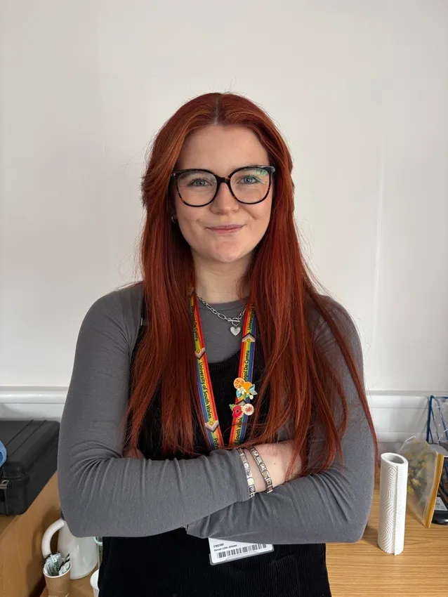 Hannah Cord-Jenkins yn sefyll gyda'i breichiau wedi'u croesi yn gwenu ar y camera