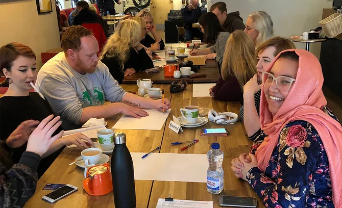 A diverse group of people gathered around a table, reviewing documents and discussing ideas together.