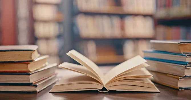 An open book on a table surrounded by many other books