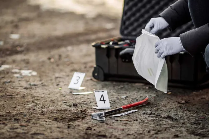 Gloved hands inspecting evidence at a crime scene.