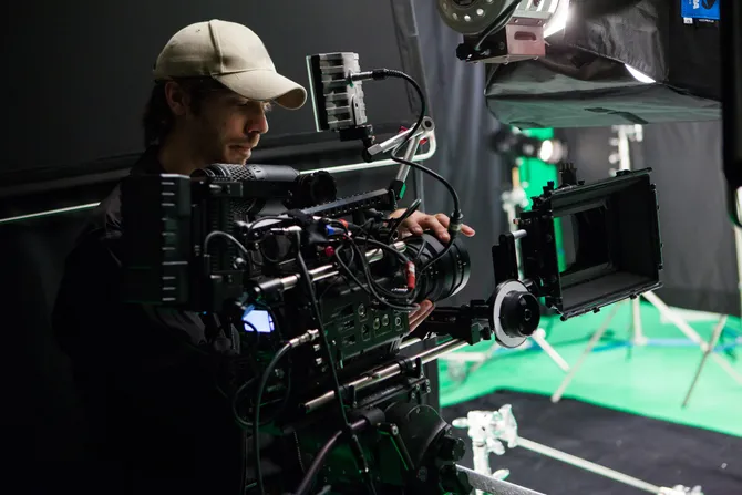 A member of a film crew using a film camera on set.