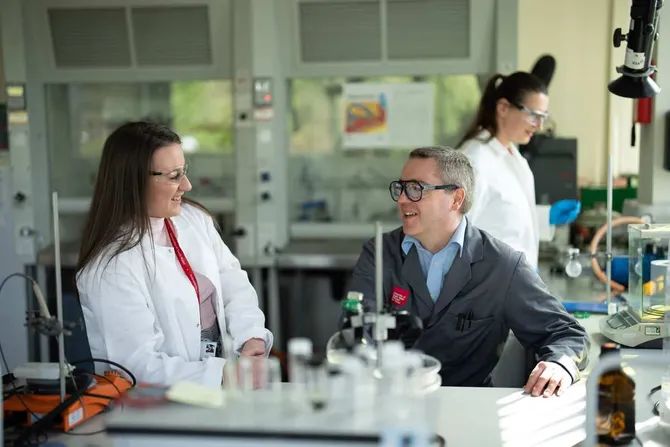 Two chemistry researchers working together in a science lab, smiling at eachother.